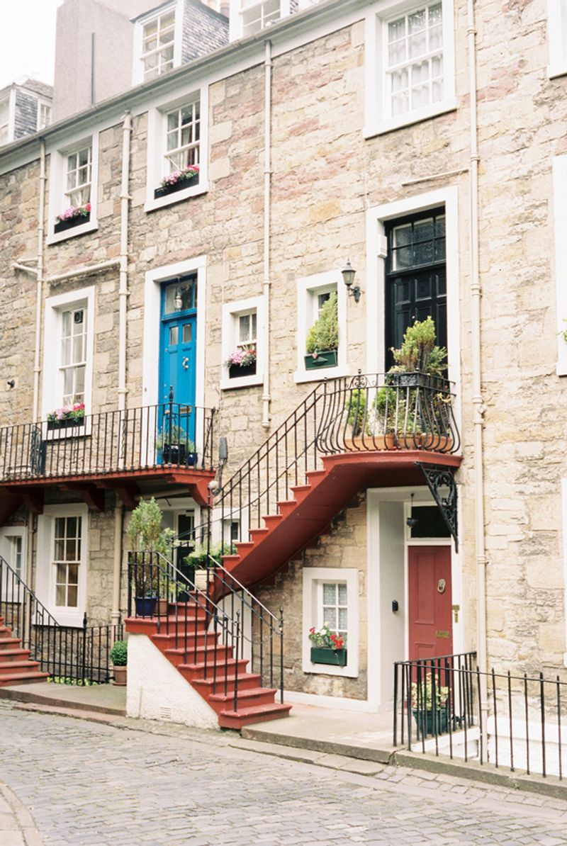 Photo of a stone townhouse with red stairs leading to the door